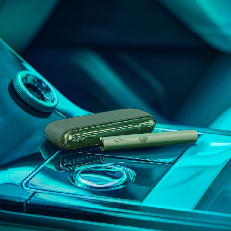 Sage green IQOS heated tobacco device on reflective surface